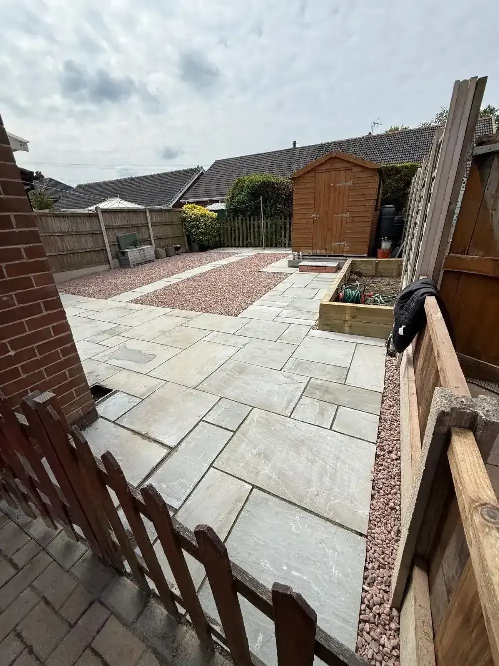 Sandstone patio with red gravel strip and raised bed