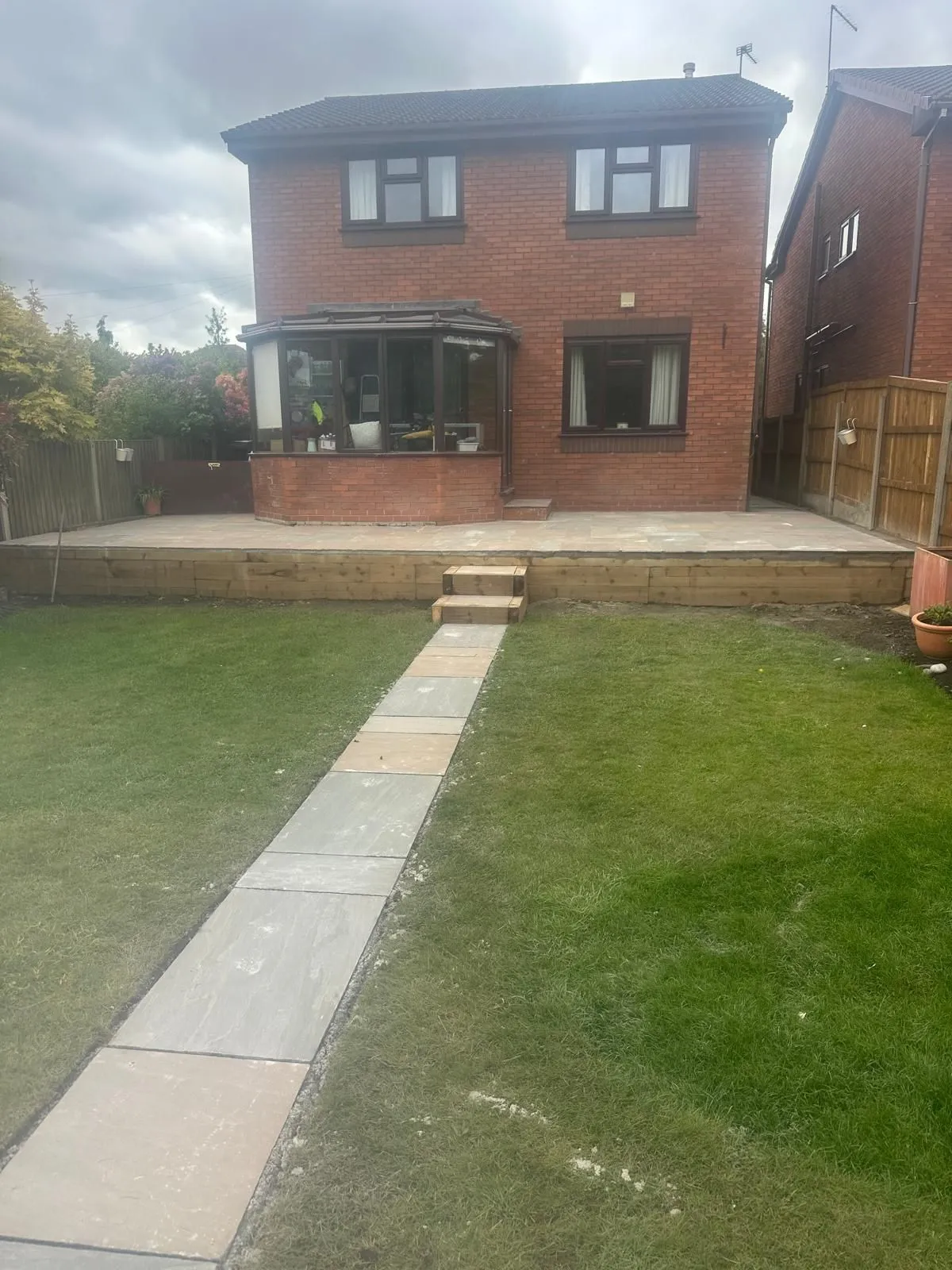 Sandstone path across the lawn to a raised patio