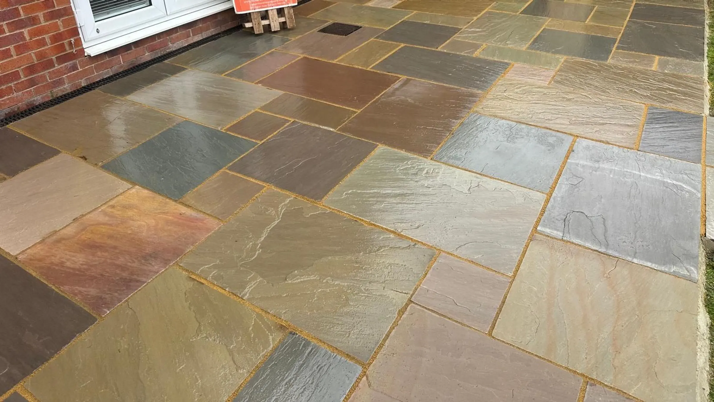 Multi-colour riven sandstone patio behind a house in Manchester