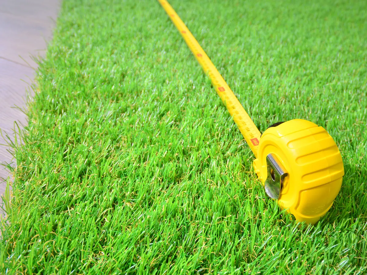 Artificial grass being measured beside paving