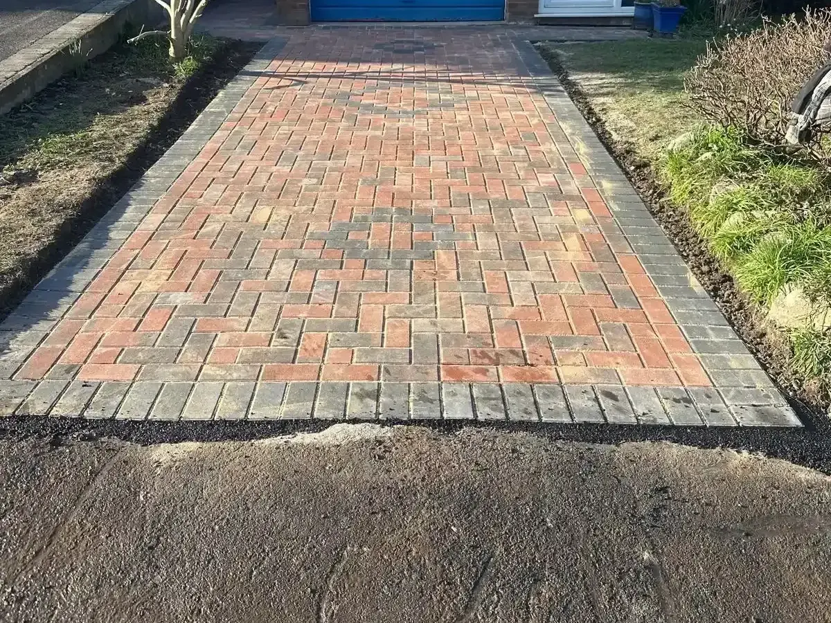 Red and brindle block paved driveway leading to a garage in Manchester