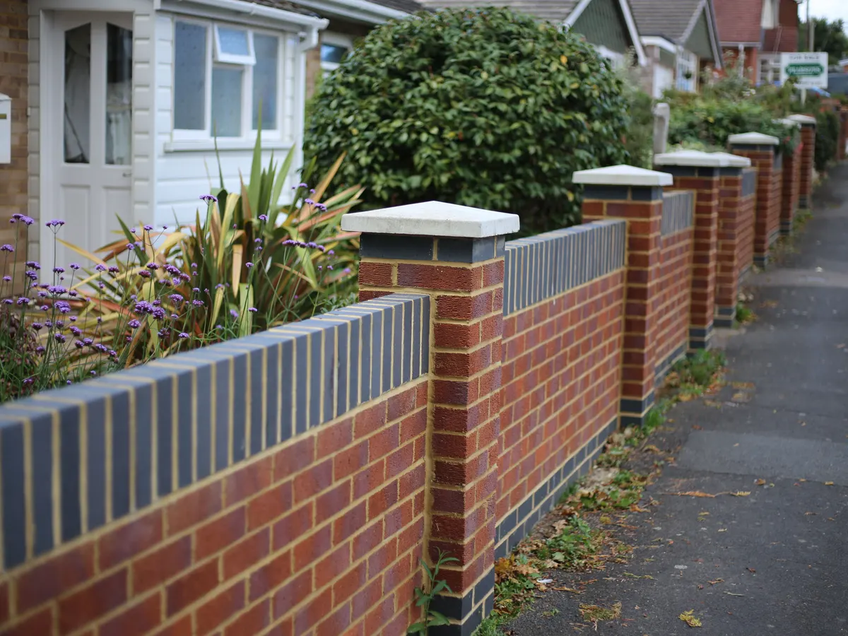 Red brick front wall with blue brick coping and piers