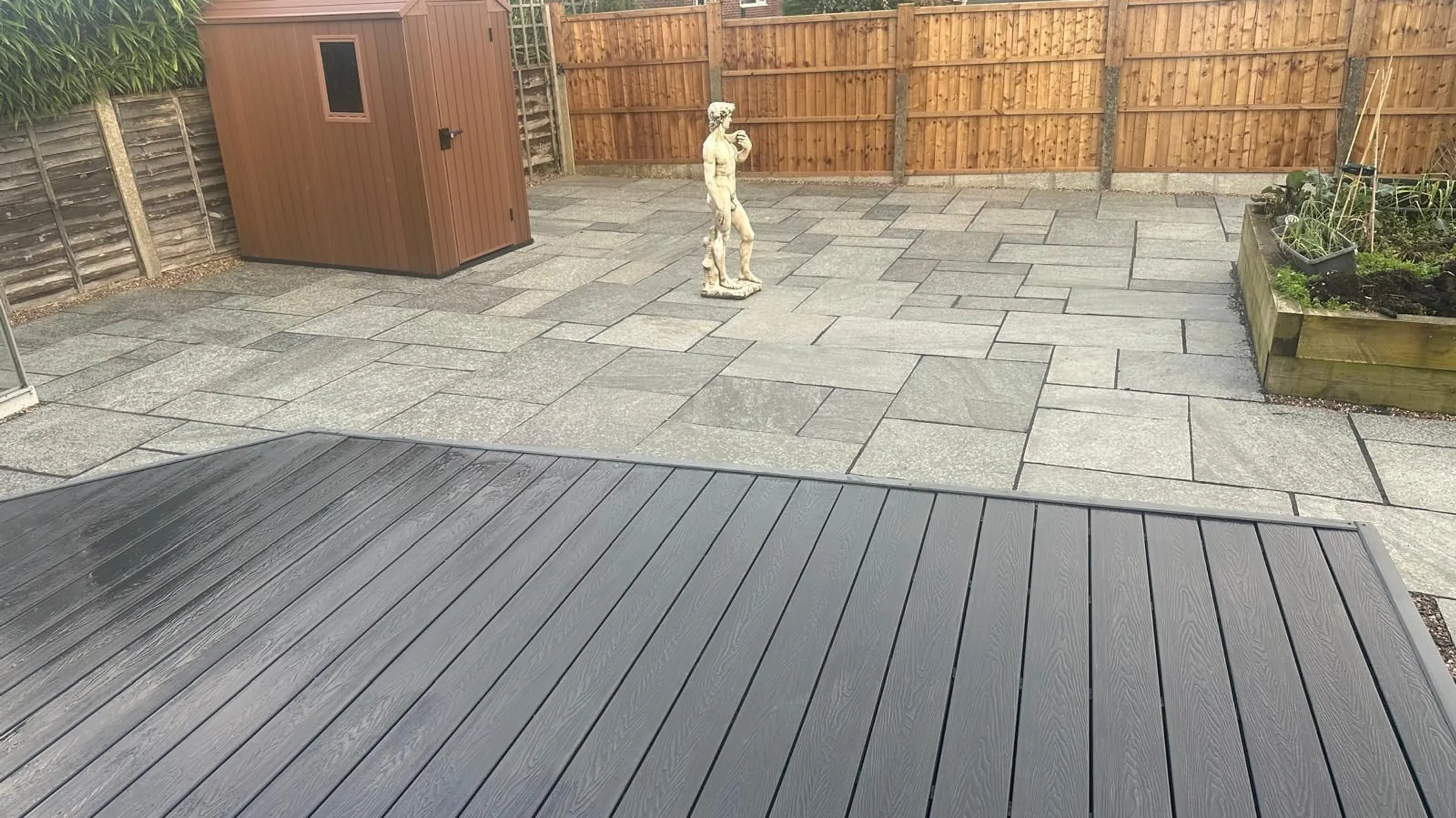 Dark grey composite deck beside a sandstone patio in a Manchester garden