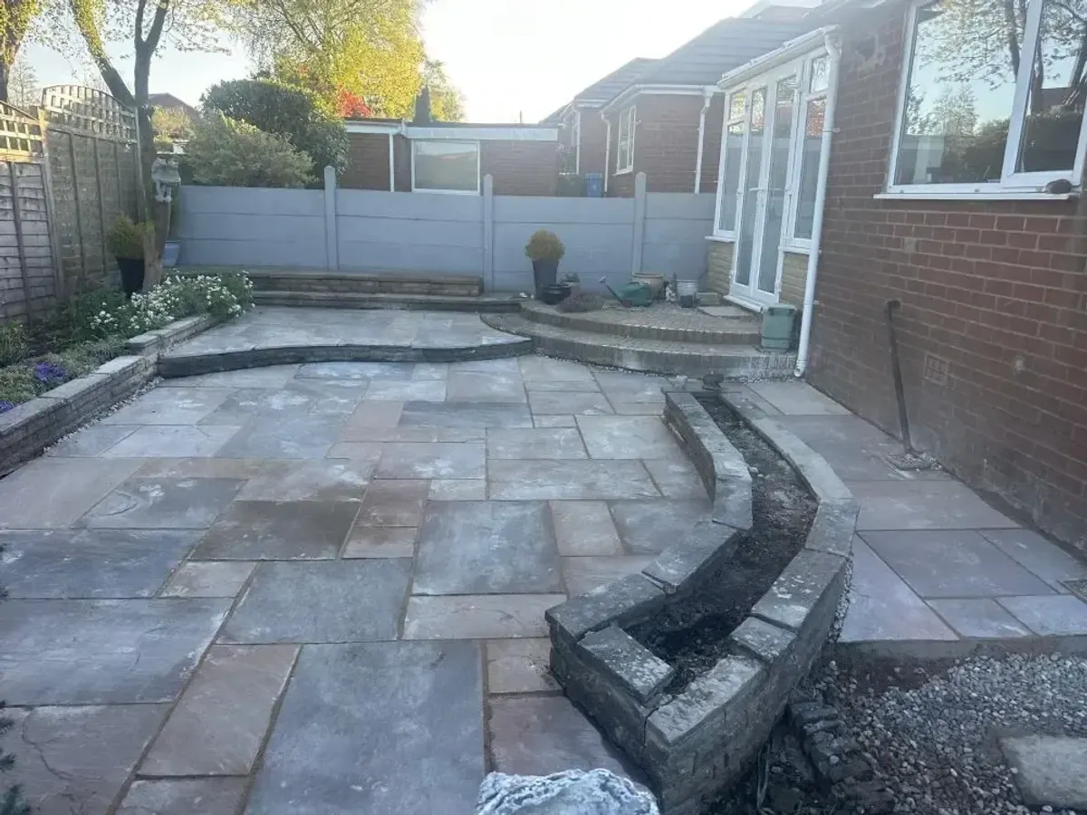 Curved stone retaining wall under construction beside a patio in Manchester