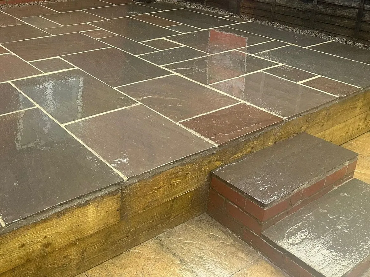 Raised multi colour sandstone patio on sleepers with a brick step in Manchester