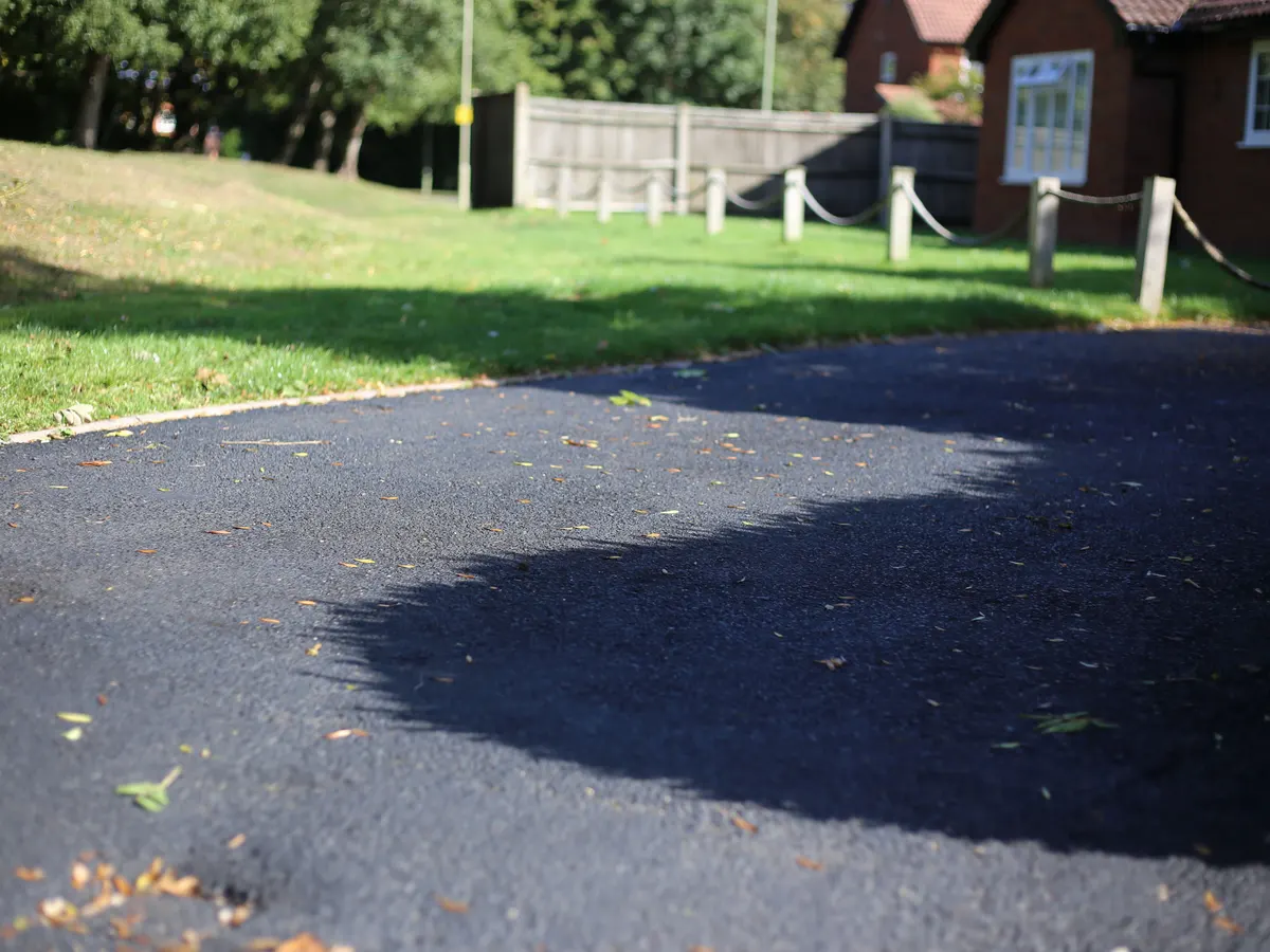 Curved tarmac driveway beside a lawn